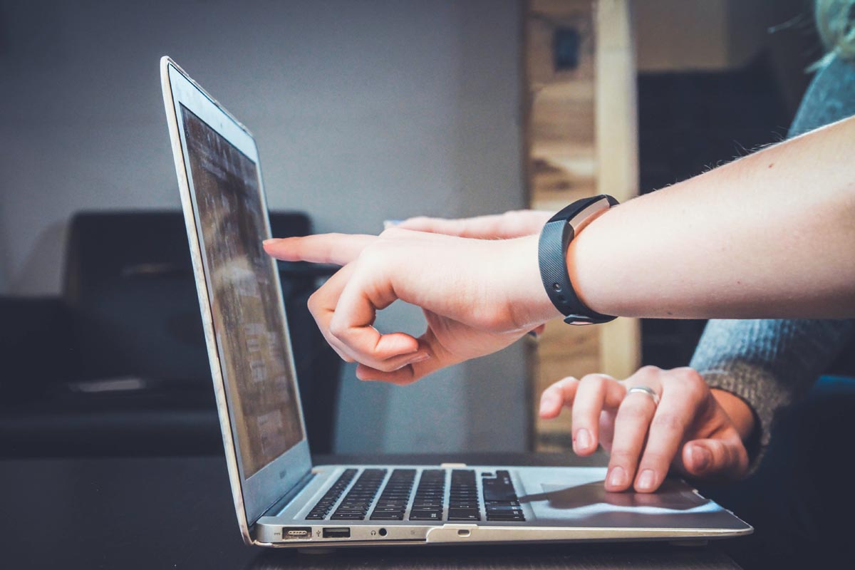 person pointing at a laptop screen
